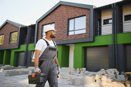 Professional plumber and repairman stands in the background of the cottage. The concept of the job...