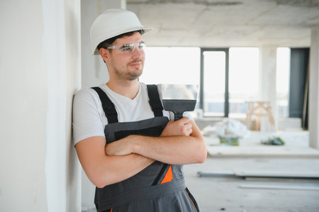 Construction site manager standing wearing helmet, thinking at construction site. Portrait of mixed race manual worker or architect.の写真素材