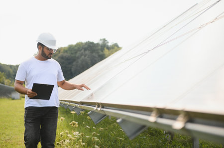 Male arab engineer standing on field with rows of solar panels.の写真素材