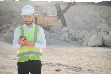 Worker in hardhat standing in stone quarry.