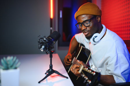 african american man with guitar in recording studio.