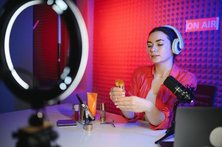 Famous blogger. Cheerful female vlogger is showing cosmetics products while recording video and giving advice for her beauty blog.の写真素材