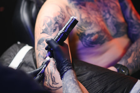 tattoo artist demonstrates the process of getting black tattoo with paint. Master works in black sterile gloves.の写真素材