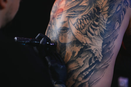 Shot of a tattoo artist hands forming perfect lines on man back with ink.の写真素材