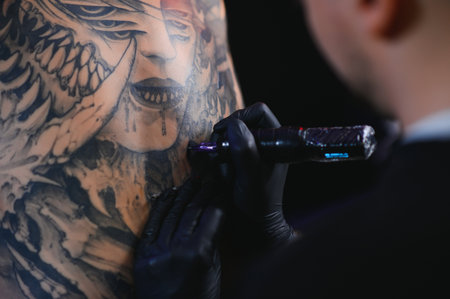 Shot of a tattoo artist hands forming perfect lines on man back with ink.の写真素材