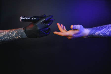 Close up cropped photo of tattooer master artist male hold in hand machine black ink in jar,...