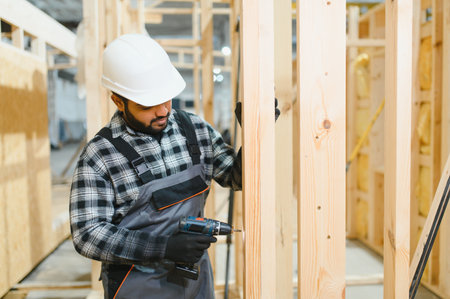 Modern modular house. Indian worker works on the construction of a wooden house.