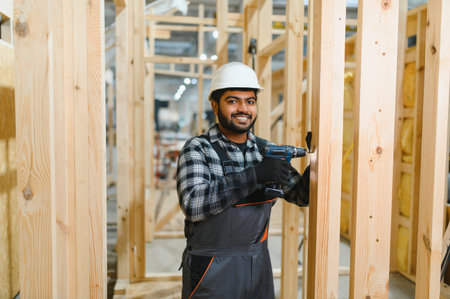 Modern modular house. Indian worker works on the construction of a wooden house.