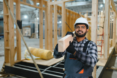 Construction of modular houses. Male Indian construction worker in uniform and hard hat at...