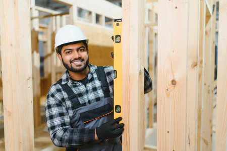 Construction of modular houses. Male Indian construction worker in uniform and hard hat at construction site.の写真素材