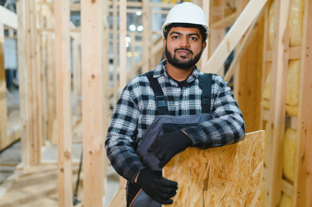 Modern modular house. Worker works on the construction of a wooden house.の写真素材