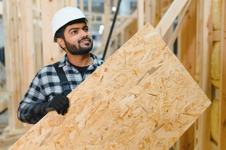 Modern modular house. Indian worker works on the construction of a wooden house.の写真素材