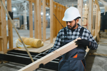 Modern modular house. Indian worker works on the construction of a wooden house.の写真素材
