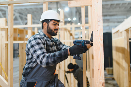 Modern modular house. Indian worker works on the construction of a wooden house.の写真素材