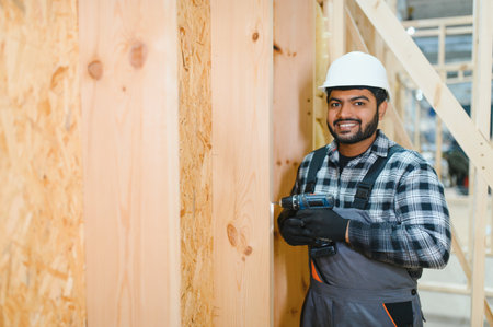 Construction of modular houses. Male Indian construction worker in uniform and hard hat at construction site.の写真素材