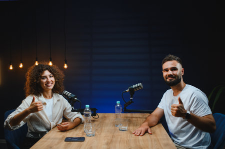 Two content creators gesturing thumbs up while recording a podcast episode in a professional studio