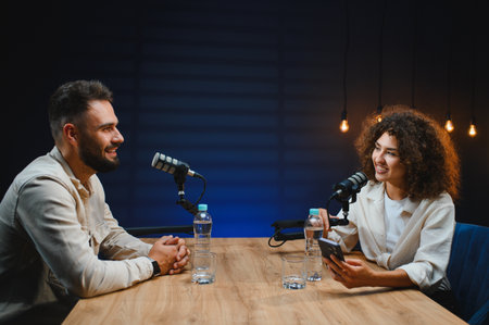 Two content creators recording a podcast in a professional studio, engaging in conversation and...