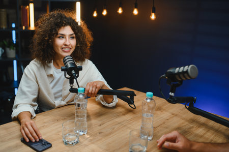Two podcasters recording audio content in a professional studio, using microphones and a mixing...