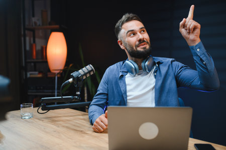 Content creator pointing finger upward while recording a video blog in a well equipped home studio,...