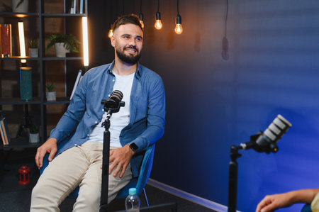 Content creator smiling and recording podcast in professional studio with microphones and led lightsの写真素材