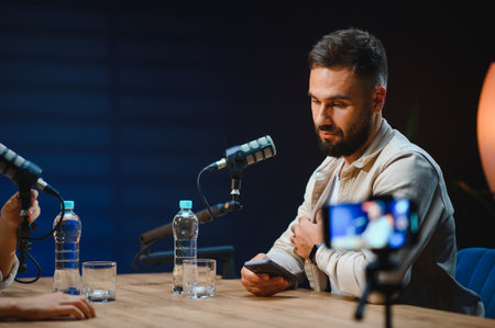 Two content creators recording a podcast in a professional studio, using microphones and a...