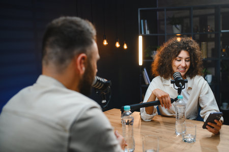 Two content creators recording a podcast episode in a professional studio, using microphones and a...