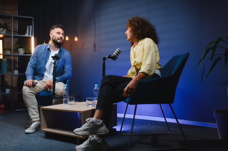 Two content creators recording a podcast in a professional studio, engaging in conversation and sharing their expertiseの写真素材