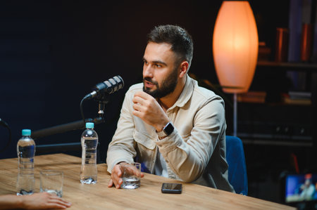 Content creator speaking into a microphone while recording a podcast in a professional studio,...