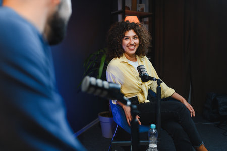 Two podcasters smiling and talking during a podcast recording session in a professional studio