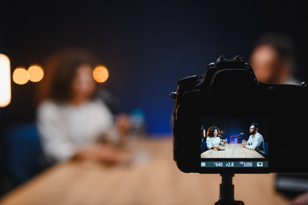 Digital camera recording podcasters at work in studio, creating online content for their audience