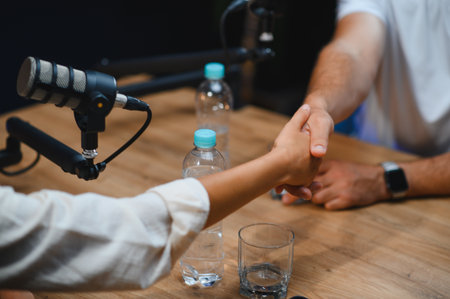 Two podcasters shaking hands after successfully recording a podcast episode in a professional studio