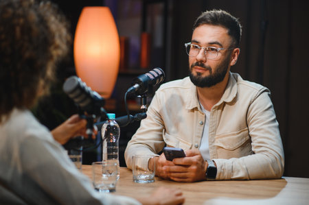 Two content creators recording podcast in home studio using professional microphone and smartphone