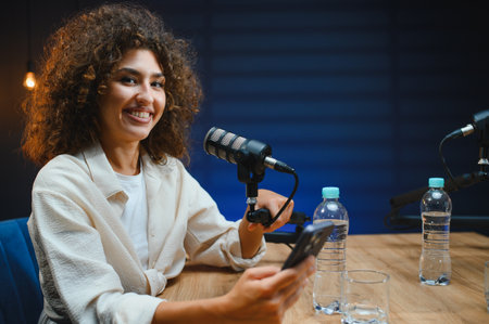 Young woman recording an audio podcast in a professional studio, using a high quality microphone and...