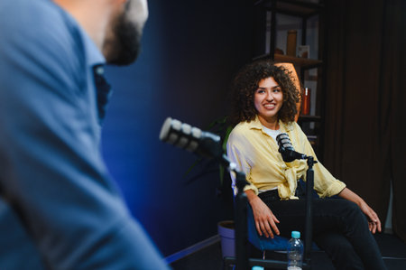 Two content creators engaging in a podcast recording session within a professional studio, utilizing...