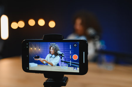 Influencer recording video blog about new mobile phone using professional microphone and smartphone...