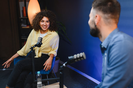 Two content creators smiling and talking during a podcast recording session in a professional studio