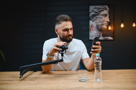 Video blogger recording audio content using professional microphone and smartphone in modern studioの写真素材