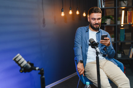 Content creator using smartphone and professional microphone, recording podcast episode in home studioの写真素材