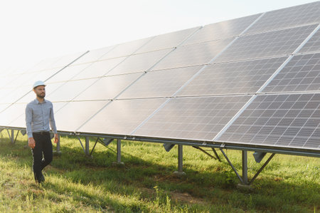 Engineer walking along solar panel array, performing important inspection of photovoltaic system for...