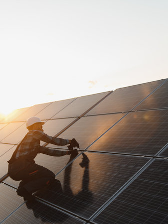 Technician installing solar energy panels on a rooftop, harnessing sun power for sustainable...