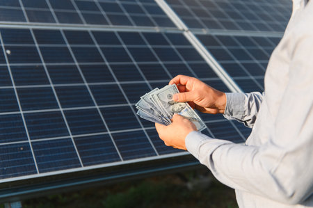 Person is holding us dollar banknotes, symbolizing green energy investment, cost savings, and profit...