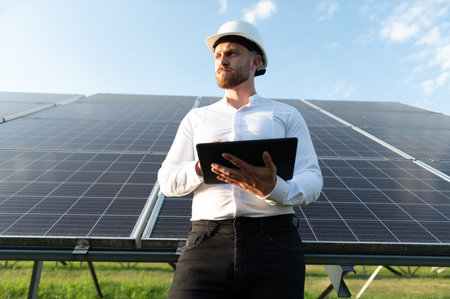 Engineer holding a tablet, inspecting solar panels and monitoring clean energy production in a...