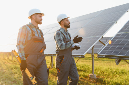 Engineers wearing hard hats and uniforms inspecting solar panels, discussing installation and...