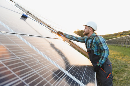 Worker cleaning a solar panel array, performing maintenance at a photovoltaic power plant for...