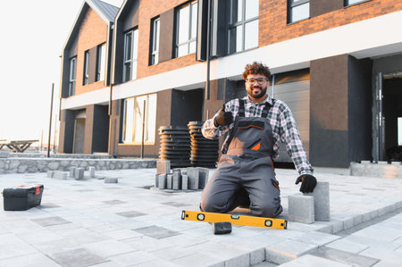 Happy worker giving a thumbs up in front of a new townhouse, showing satisfaction with completed...