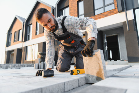 Worker installing paving stones on a new driveway. Hard work for home improvement. Construction of...
