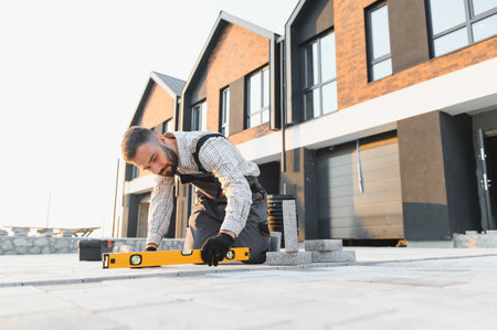 Man laying pavers for building renovation. Construction worker installing patio paving slabs with a...