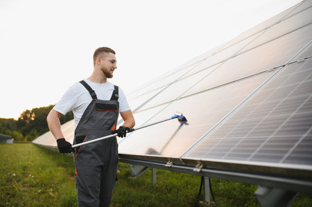 Engineer cleaning solar panel array. Technician performing maintenance on photovoltaic installation for green energy productionの写真素材