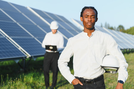 Two engineers analyzing solar farm operations, focusing on renewable energy and sustainable...