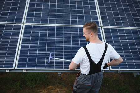 Technician cleaning solar panel using a squeegee, ensuring optimal performance and promoting...